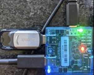 青い LED が点灯した Microsoft USB テスト ツール (MUTT) デバイスの写真。